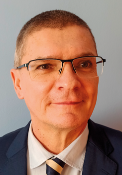 Formális öltözet, amely egy sötétkék zakóból, világoskék ingből és kék-sárga csíkos nyakkendőből áll.