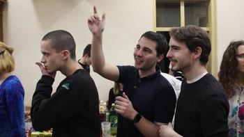 Csoport emberek egy asztal körül, amelyen különféle italok vannak elhelyezve.