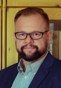 Elegáns öltözetű férfi fa szekrények előtt áll