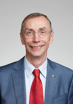 Egy férfi elegáns öltönyt visel, piros nyakkendővel.