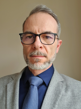 Elegáns férfi öltözet, szürke zakó, sötétkék ing és nyakkendő látható a képen.