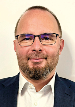 Férfi fehér inget és sötétkék zakót visel, formális öltözetben látható.