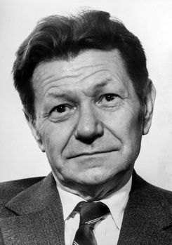 Férfi öltönyben és nyakkendővel, elmosódott fejjel, fekete-fehér kép.