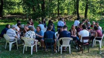 Fiatalok egy körben ülnek a szabadban, valószínűleg egy közösségi eseményen vagy találkozón.