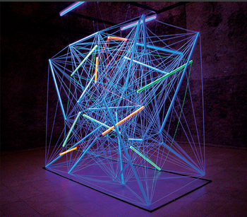 Modern művészeti installáció, geometriai forma neonfényekkel és színes szálakkal.